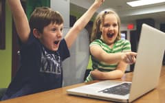 Двое детей радуются за компьютером